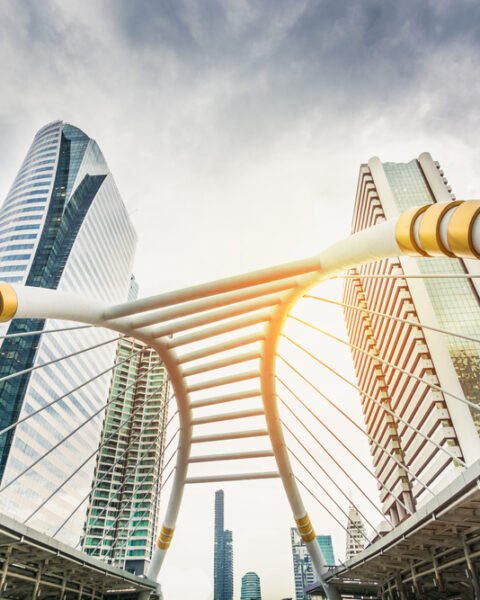 A scenic view of a bridge over Bangkok, framed by towering buildings that define the city's skyline.