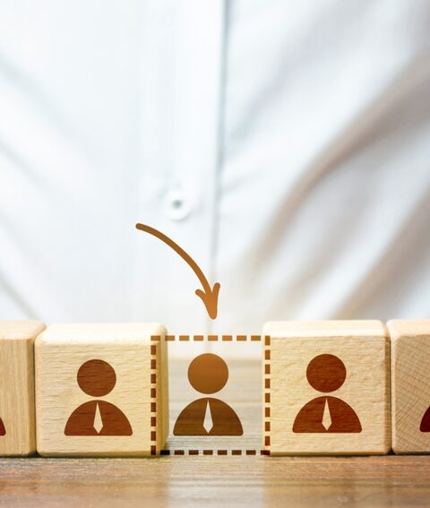 Businessman holds wooden blocks with people figures, symbolizing the impact of Labor Market in Southeast Asia Construction dynamics.