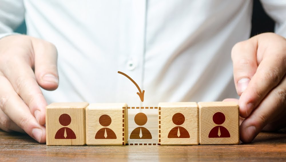 Businessman holds wooden blocks with people figures, symbolizing the impact of Labor Market in Southeast Asia Construction dynamics.