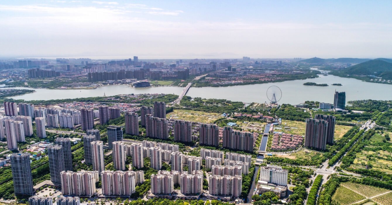 Aerial view of a bustling cityscape filled with numerous buildings and urban structures under a clear blue sky, representing Real Estate Development Southeast Asia.