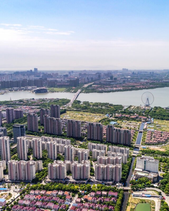 Aerial view of a bustling cityscape filled with numerous buildings and urban structures under a clear blue sky, representing Real Estate Development Southeast Asia.