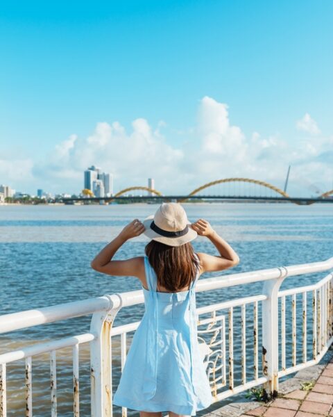 A woman in a stylish hat gazes thoughtfully at the expansive city skyline before her, capturing a moment of reflection.