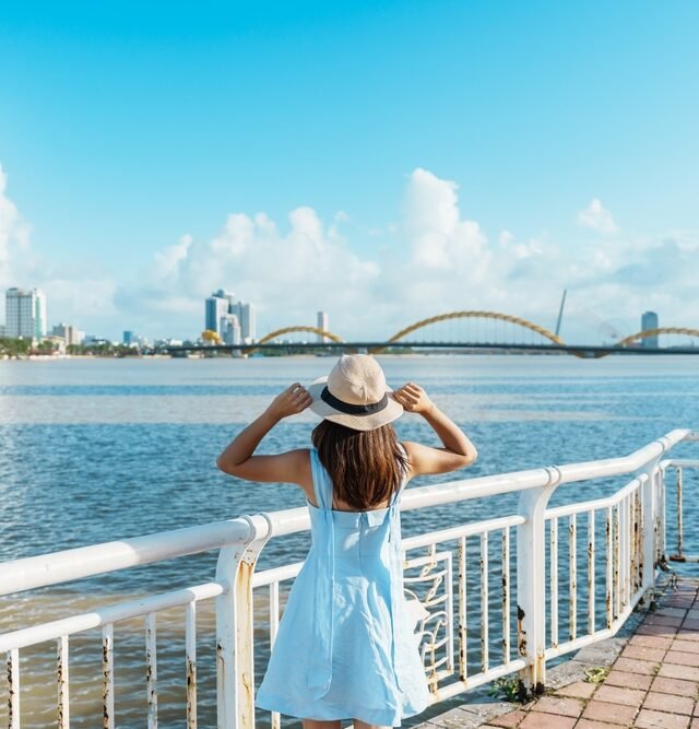 A woman in a stylish hat gazes thoughtfully at the expansive city skyline before her, capturing a moment of reflection.