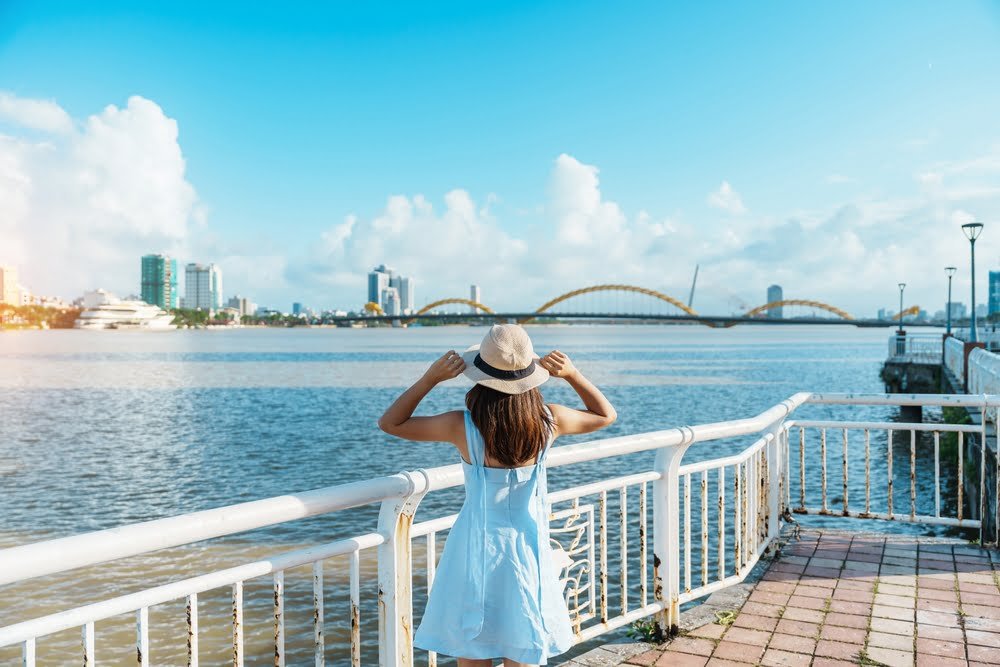 A woman in a stylish hat gazes thoughtfully at the expansive city skyline before her, capturing a moment of reflection.