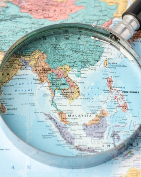 Magnifying glass over a map focusing on Southeast Asian countries, symbolising Southeast Asia Urban Development.