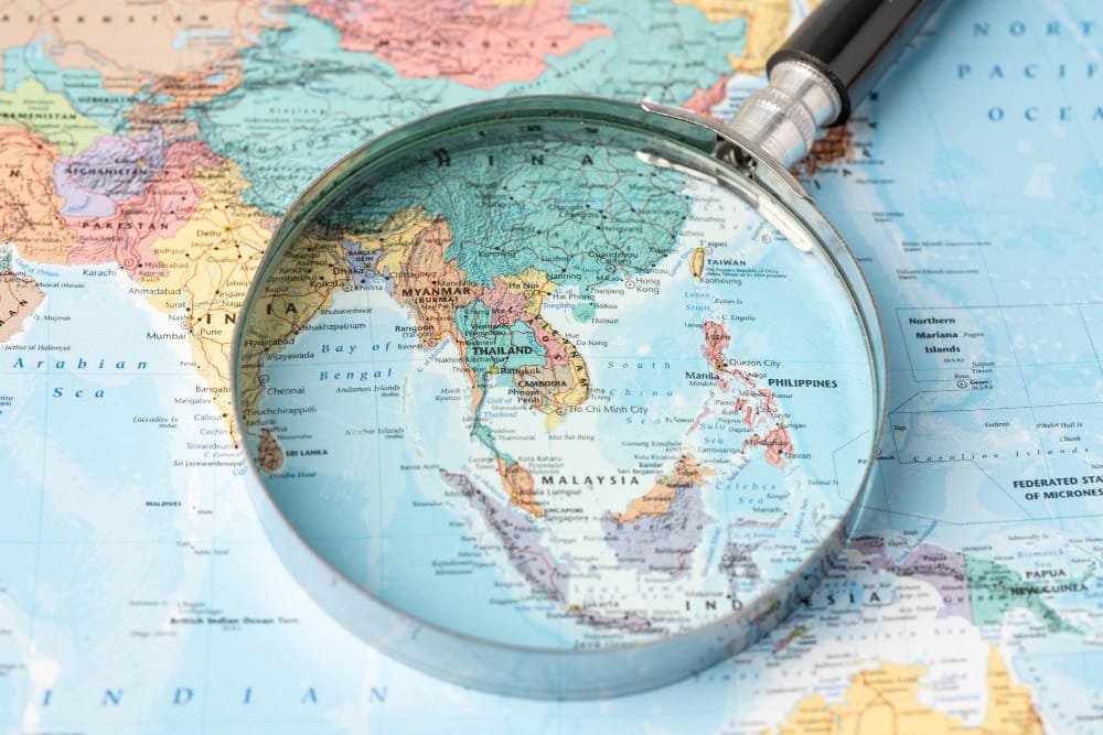 Magnifying glass over a map focusing on Southeast Asian countries, symbolising Southeast Asia Urban Development.