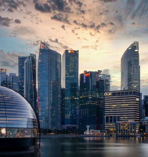 Dusk view of a Singapore's skyline with modern buildings and a glass dome on the waterfront, showing the Southeast Asia Real Estate Trends.