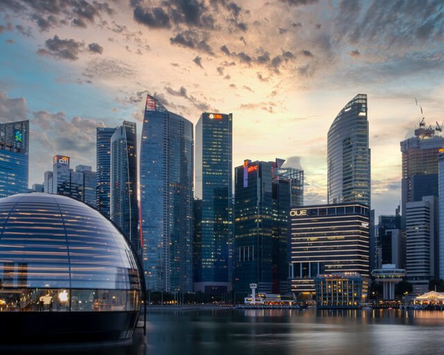 Dusk view of a Singapore's skyline with modern buildings and a glass dome on the waterfront, showing the Southeast Asia Real Estate Trends.