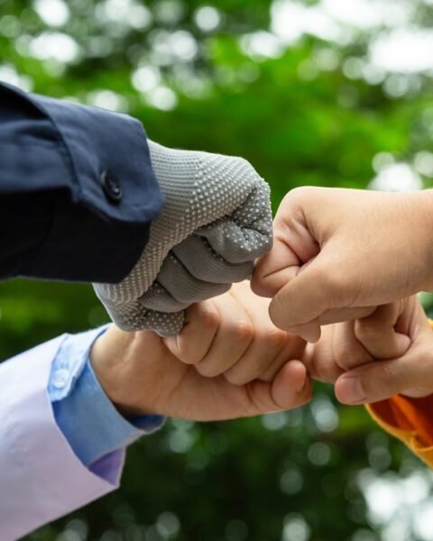 Four people making a fist bump gesture with a blurred green background, symbolising the collaboration between the government, the private sector and the public (Public-Private Partnerships Southeast Asia).