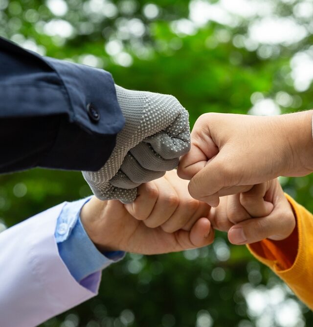 Four people making a fist bump gesture with a blurred green background, symbolising the collaboration between the government, the private sector and the public (Public-Private Partnerships Southeast Asia).