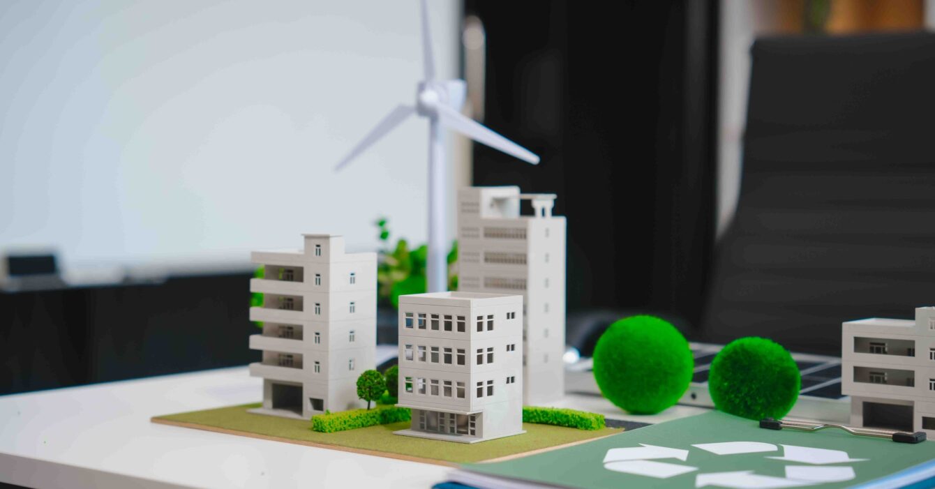 Energy-Efficient Buildings Southeast Asia: Model of a sustainable city with small-scale buildings, wind turbine, and greenery on a desk.