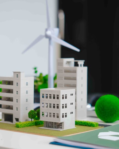 Energy-Efficient Buildings Southeast Asia: Model of a sustainable city with small-scale buildings, wind turbine, and greenery on a desk.