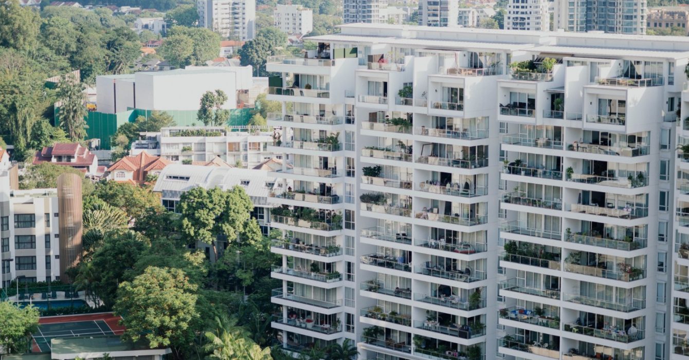 Affordable Housing in Southeast Asia: Urban landscape with modern high-rise buildings and lush green trees.