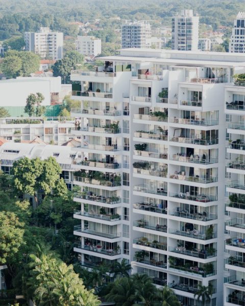 Affordable Housing in Southeast Asia: Urban landscape with modern high-rise buildings and lush green trees.