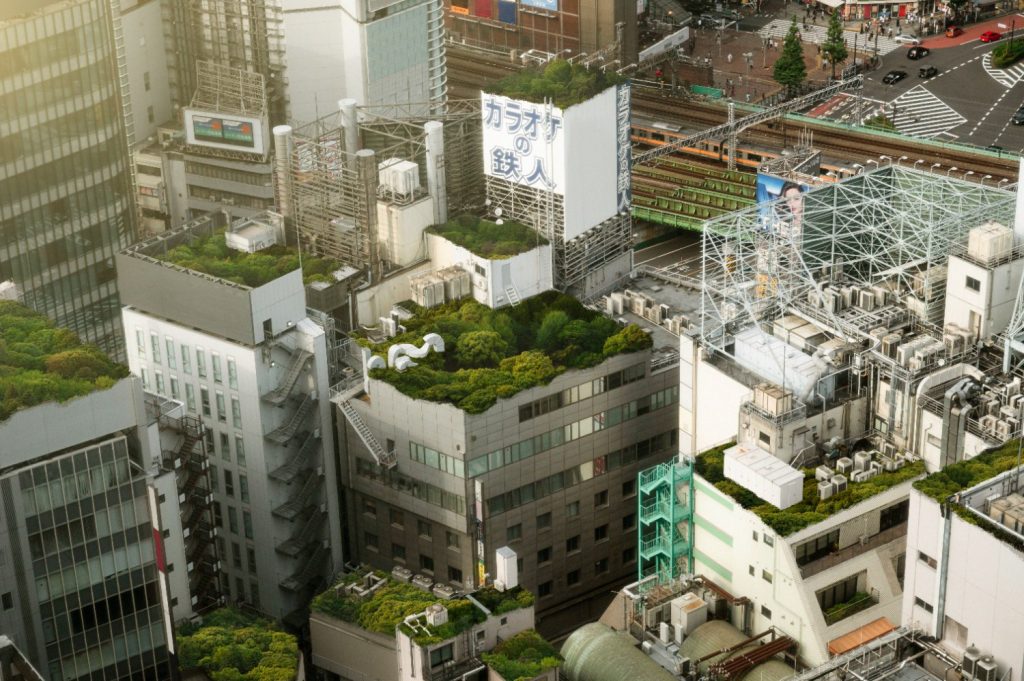 Sustainable Construction Practices in Southeast Asia: Aerial view of dense urban buildings with rooftop greenery and industrial structures.