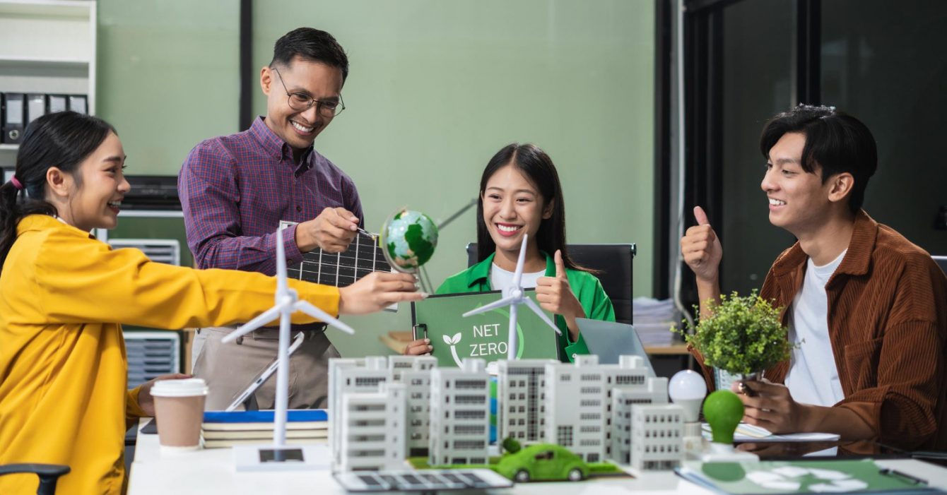 Sustainable Construction Practices in Southeast Asia: Team of professionals with sustainable energy models on a table, interacting positively.