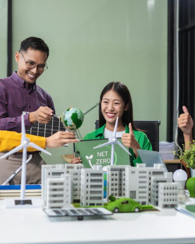 Sustainable Construction Practices in Southeast Asia: Team of professionals with sustainable energy models on a table, interacting positively.