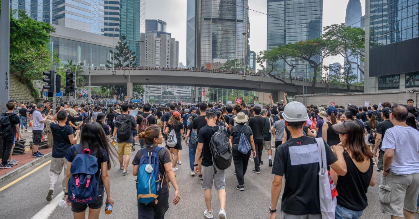 Urbanization Trends in Southeast Asia: Crowd marching in an urban environment with skyscrapers and an overpass.