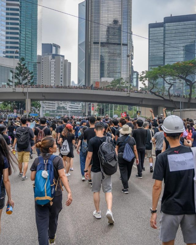 Urbanization Trends in Southeast Asia: Crowd marching in an urban environment with skyscrapers and an overpass.