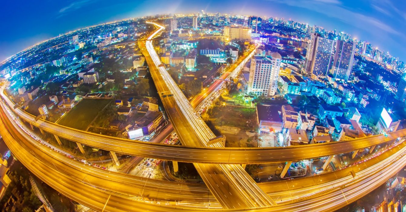 Infrastructure Investment Opportunities: Aerial view of a city at night with illuminated, intertwining highways.