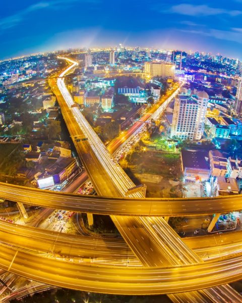 Infrastructure Investment Opportunities: Aerial view of a city at night with illuminated, intertwining highways.